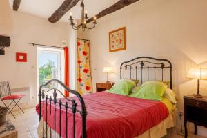 a bedroom with a bed with a red comforter at Chez Bacchus - Chambres in Gras
