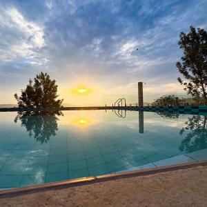 a swimming pool with a sunset in the background at Umutuzo Lodge Kivu Lake in Buhoro