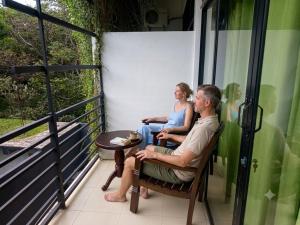 a man and woman sitting on the porch of a house at Lavish Resort Sigiriya in Inamaluwa