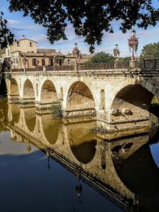 a bridge over a body of water with a building at La Garrigue in Calvisson
