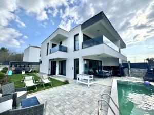 a large white house with a swimming pool at Marina Seaside Escape in Malinska