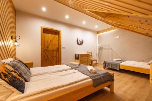 a bedroom with two beds and a wooden ceiling at Apartamenty pod Góralskim Niebem in Gliczarów Górny