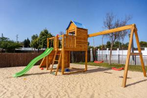 a wooden playground with a green slide and a ladder at Kampaoh Lago de Arcos in Arcos de la Frontera