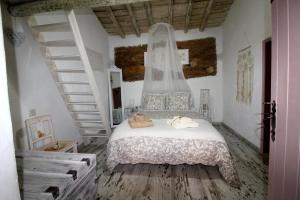 a bedroom with a white bed with a staircase at Casinha das Portas Amarelas in Monsaraz