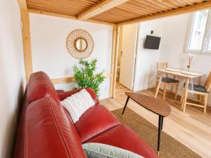 a living room with a red leather couch and a table at Studio cosy avec terrasse - Proche château in Fougères