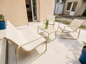 three white chairs and a table on a patio at Studio cosy avec terrasse - Proche château in Fougères +4 photos