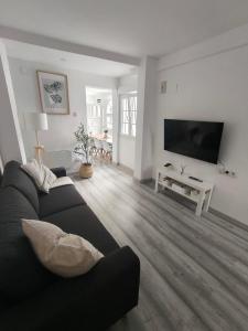 a living room with a black couch and a flat screen tv at Casa La Cordelera in Salinas