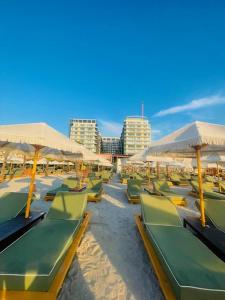 a beach with green lounge chairs and umbrellas at VCV Apartments in Mamaia Sat/Năvodari