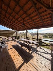 a wooden deck with picnic tables and chairs on it at Cabaña de campo in Tanti