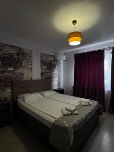 a bedroom with a large bed with a purple curtain at Vila Adelin in Tăşnad