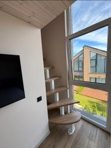a room with a tv and a book shelf and a window at Kotedžas su baseinu ir pirtimi in Palanga