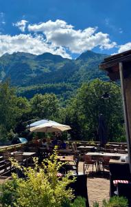 a patio with tables and umbrellas with mountains in the background at Hôtel Le Monal in Sainte-Foy-Tarentaise
