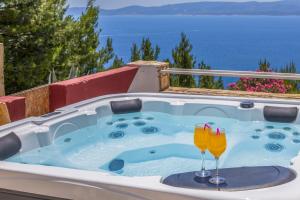 a jacuzzi tub with two champagne glasses at White Cove Apartments in Lokva Rogoznica
