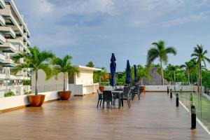 a balcony with tables and chairs and palm trees at Explore Nature & Beaches! Nuevo Nayarit Condo in Nuevo Nayarit
