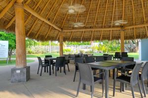 a restaurant with tables and chairs under a straw umbrella at Explore Nature & Beaches! Nuevo Nayarit Condo in Nuevo Nayarit
