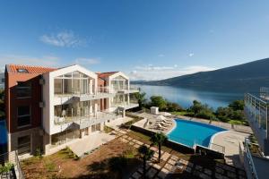a large house with a swimming pool next to a lake at Acacia Hill Apartment C01 with shared pool in Đenovići
