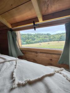 a bed with a window with a view of a field at Tiny house a la ferme in Huelgoat