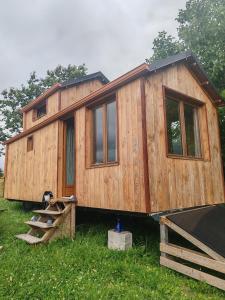 a wooden house sitting in the grass at Tiny house a la ferme in Huelgoat