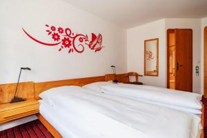 ein Schlafzimmer mit zwei weißen Betten und einem roten Schild an der Wand in der Unterkunft Typically Swiss Hotel Altana in Scuol