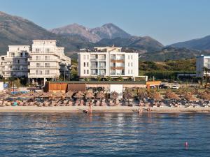 a beach with umbrellas and buildings and the water at Maor Hotel in Vlorë
