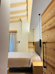 a bedroom with a bed and a wooden wall at Hotel Al Prato in Fiera di Primiero