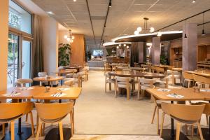 a dining room with wooden tables and chairs at Novotel Saint-Quentin en Yvelines in Magny-les-Hameaux