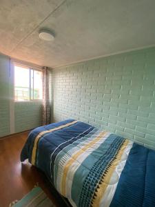 a bed in a bedroom with a brick wall at Comfortable apartment steps from Portal Belloto in Quilpué