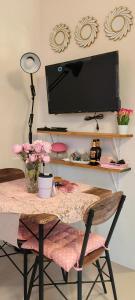 a room with a table with a television on a wall at Rooms in Bloom in Tarlac