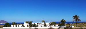 a white house with palm trees and the ocean at El Chalet Los Escullos in Almería
