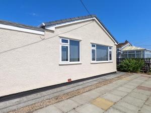 a white house with white windows and a fence at Ger y Mynydd, 2 Cae Ty Coch in Brynteg