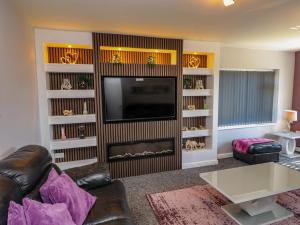 a living room with a couch and a television at Ger y Mynydd, 2 Cae Ty Coch in Brynteg