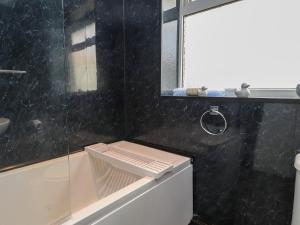 a black tiled bathroom with a tub and a mirror at Ger y Mynydd, 2 Cae Ty Coch in Brynteg +19 photos