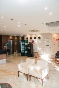 a lobby with two white chairs and a table at Easy Hotel Cachoeiro de Itapemirim by Atlantica in Cachoeiro de Itapemirim