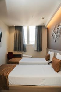 a hotel room with two beds and a window at Easy Hotel Cachoeiro de Itapemirim by Atlantica in Cachoeiro de Itapemirim