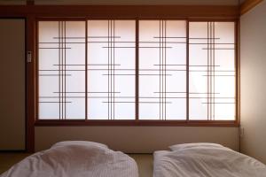 two beds in front of a window with white sheets at Kanazawa Machiya Kasaichi - Entire House Free Parking in Kanazawa