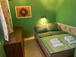 a small green room with a bed with towels on it at Apartman Jasmine in Csopak