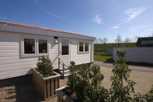 a white tiny house with plants in front of it at Chaletparc Krabbenkreek in Sint Annaland