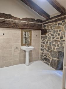 a bathroom with a sink and a stone wall at Casona Valle de Soba in Regules +48 photos