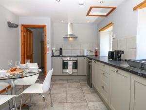 a kitchen with a table and white chairs in it at The Milk Shed in Plymtree