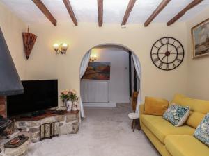 a living room with a couch and a clock on the wall at Mei's Cottage in Exeter