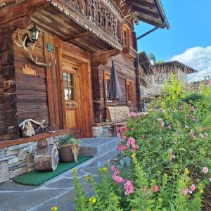 a wooden cabin with a porch and flowers in front of it at Haus Elfriede in Schwendau