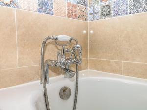 a white bath tub with a shower in a bathroom at Mei's Cottage in Exeter +32 photos