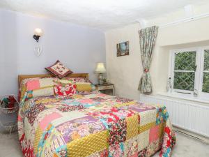 a bedroom with a bed with a colorful quilt at Mei's Cottage in Exeter
