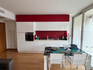 a kitchen with white cabinets and a table with chairs at Juwel am See in Castelletto di Brenzone