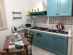 a kitchen with blue cabinets and a sink and a table at Donna Teresa in Castelbuono