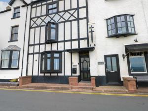 a white building with black windows and a door at Broad Beams in Neston