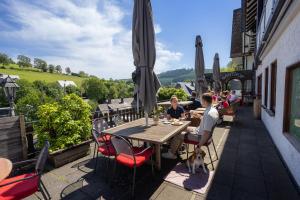 a man sitting at a table with a dog on a patio at Hotel Bischof in Schmallenberg