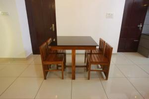 a wooden table with four chairs and a table and a door at AJ Homes - Aaron Villa in Ernakulam