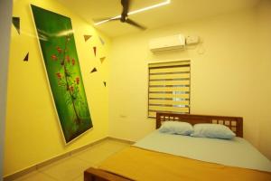 a bedroom with a bed and a painting on the wall at AJ Homes - Aaron Villa in Ernakulam