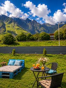 a patio with a table and chairs with mountains in the background at Relax Kazbegi Panoramic Mountain View in Kazbegi